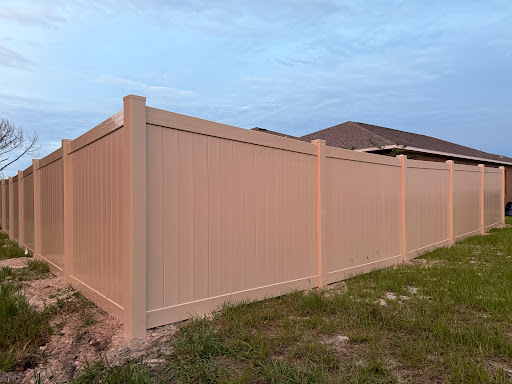 Tan vinyl privacy fence around a backyard
